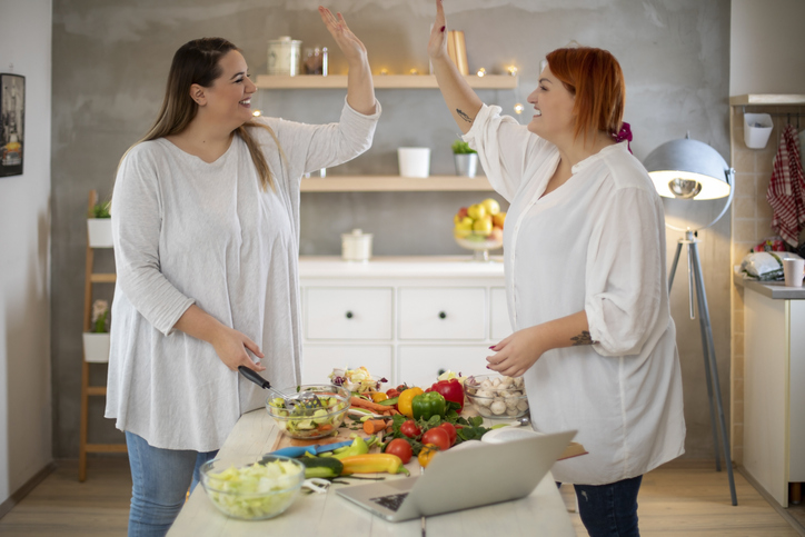 2 stevige vrouwen die salade klaarmaken