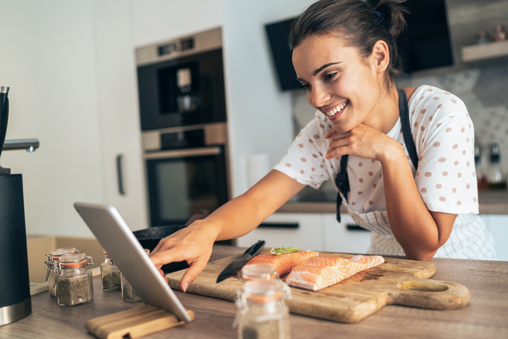 vrouw bekijkt video in de keuken over bereiden van vis