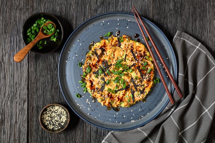 Bord met een met groenten gevulde pannenkoek op een donkeler Japans uitziende) tafel