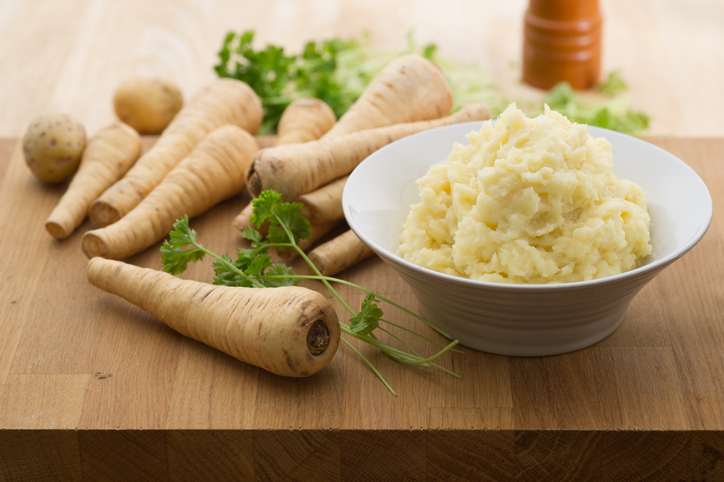 Pastinaakpuree puree van pastinaak in een schaal met hele pastinaken op de achtergrond