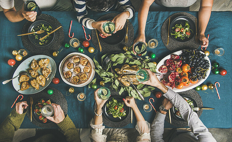 groep vreidne aan ene kersttafel vanoveaf gefotografeerd (flatlay)