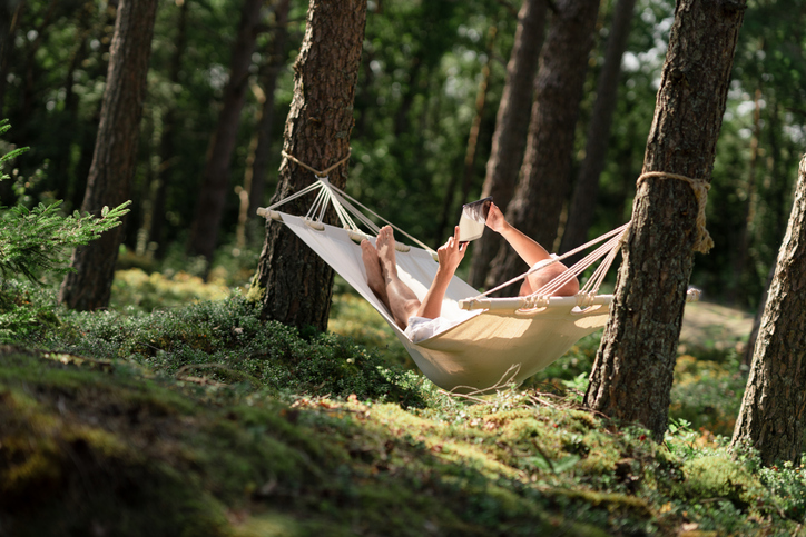 persoon liggend in een hangmat in het bos