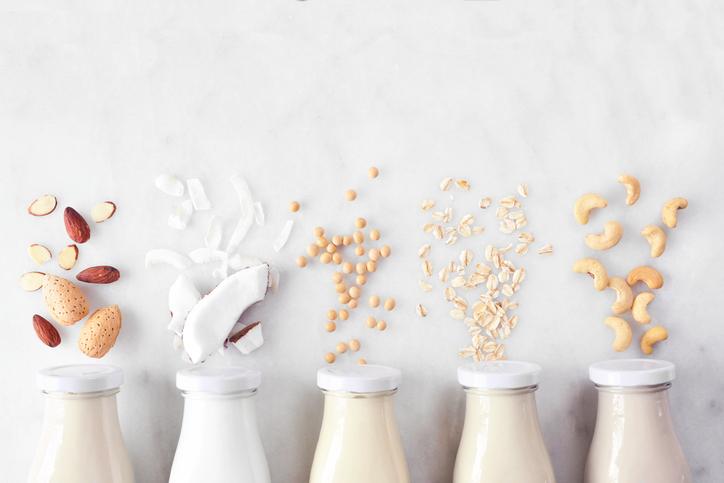 Aantal flessen melk met boven elke fles een ander plantaardig ingredient