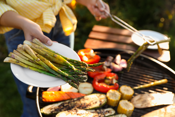 vrouw roostert groente op een barbecue buiten