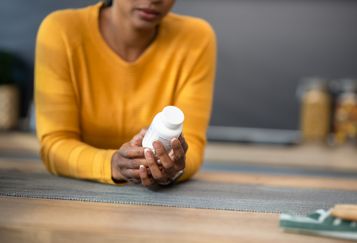 vrouw bekijkt potje met vitamines