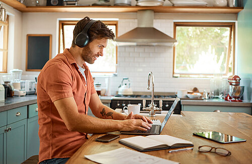 Zo wordt jouw thuiswerkdag PuurGezond Man werkend op de laptop in de keuken
