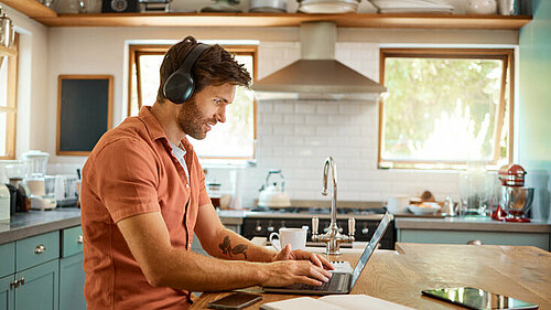 Man werkend op de laptop in de keuken