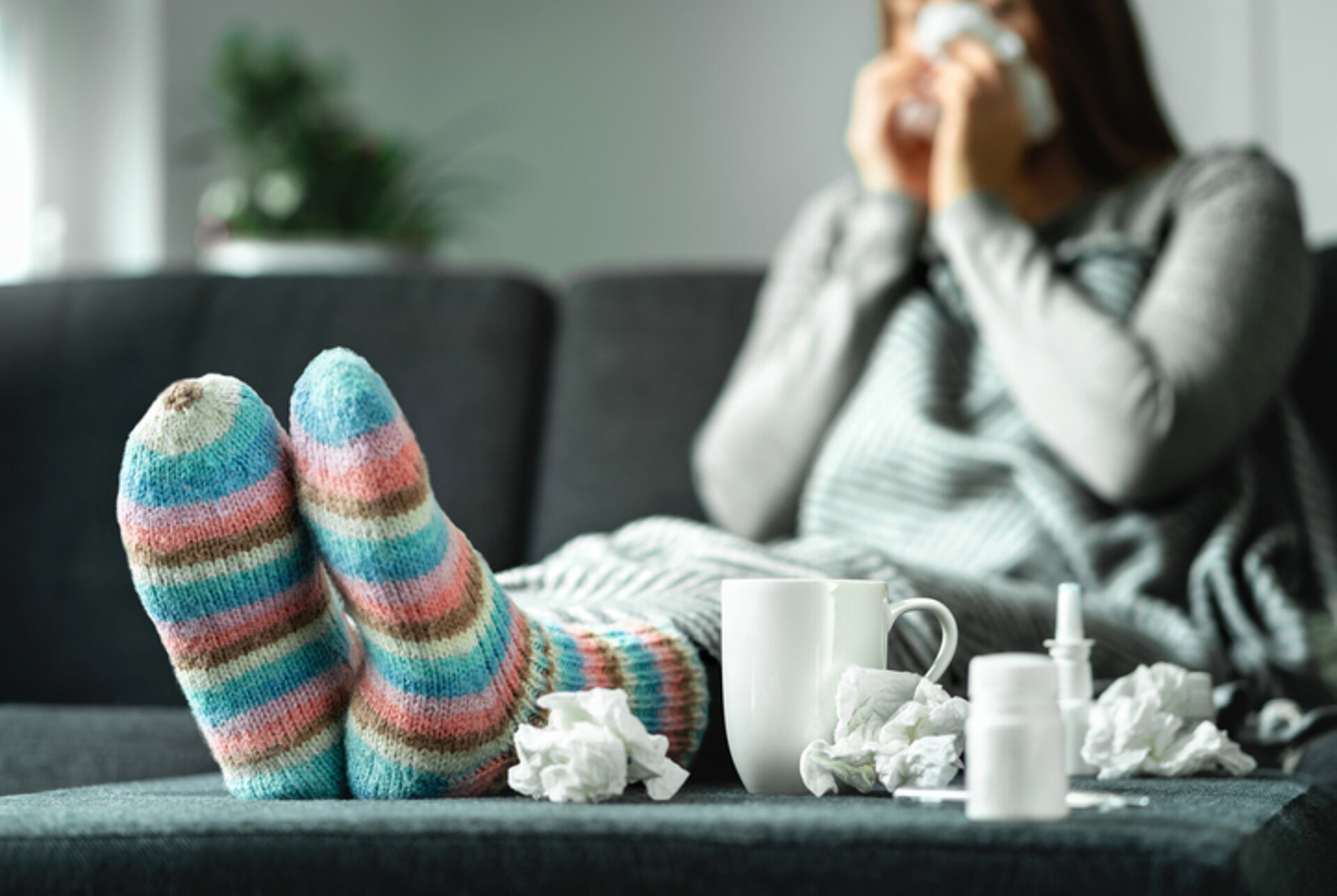 tips om je weertand te verhogen verkouden vrouw ingepakt op de bank met gebruikte papieren zakdoekjes