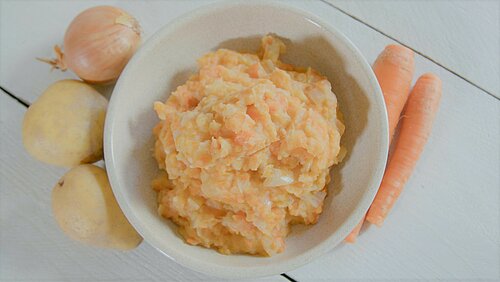 Hutspot op een wit bord met ui, aardappel en wortel