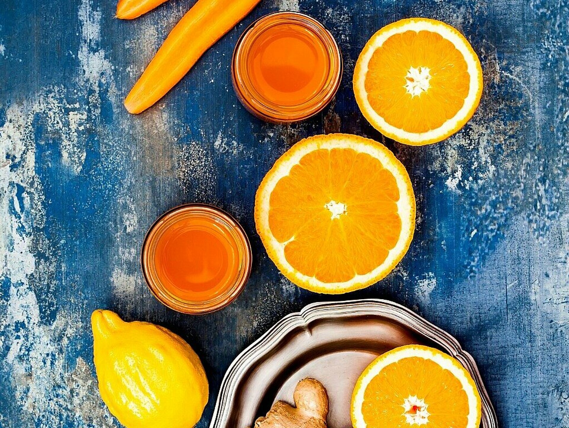 wottel, sinaasappel en gember op een tafel met een glas smoothie erbij