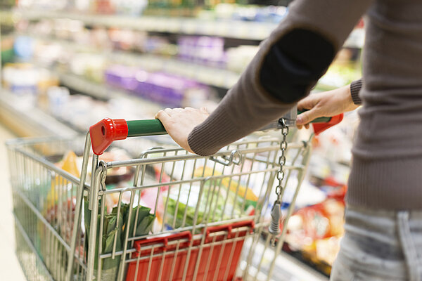 vrouw achter een winkelkarretje in de supermarkt