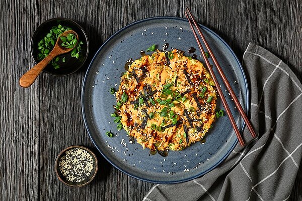 Bord met een met groenten gevulde pannenkoek op een donkeler Japans uitziende) tafel