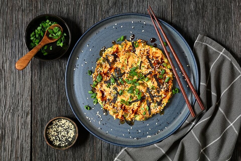 Bord met een met groenten gevulde pannenkoek op een donkeler Japans uitziende) tafel