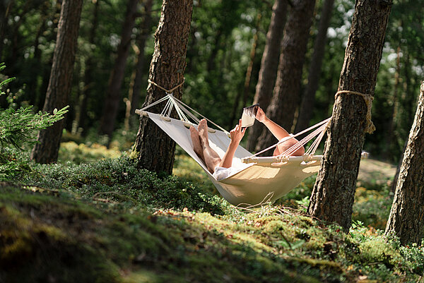 persoon liggend in een hangmat in het bos
