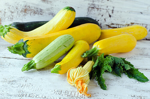 Ook dit zijn courgettes Verschillende courgettes en courgettebloemen op houten tafel