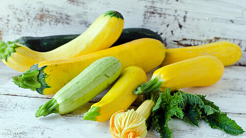 Verschillende courgettes en courgettebloemen op houten tafel