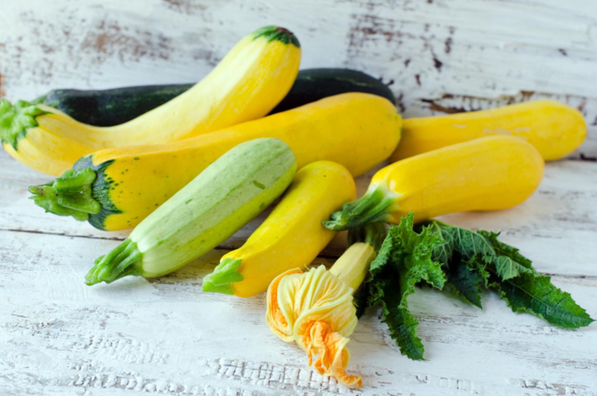 Ook dit zijn courgettes Verschillende courgettes en courgettebloemen op houten tafel
