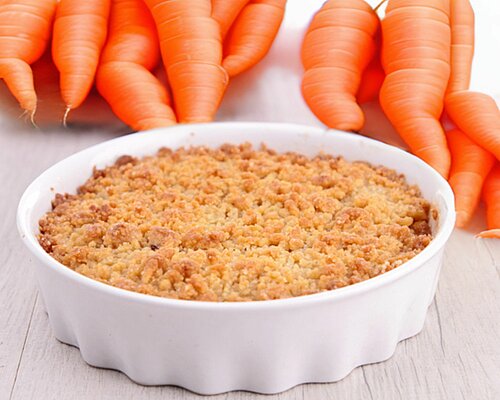 Witte schaal met oranje cake, daarachter oranje worteles
