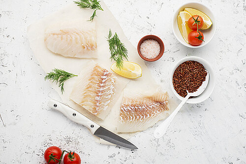 4 redenen waarom je vaker vis wilt eten 3 stukjes ongebakken kabeljauwfilet met daarbij kruiden, tomaat en citroen
