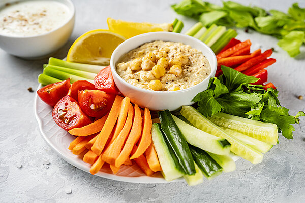 bord met gezonde snacks: rauwkost met hummus en een yoghurt dip