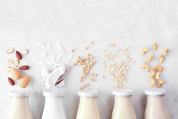 Aantal flessen melk met boven elke fles een ander plantaardig ingredient
