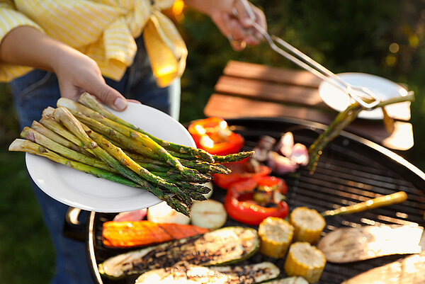 vrouw roostert groente op een barbecue buiten