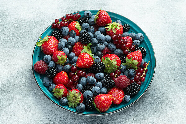 Verschillende soorten zacht zomerfruit op een blauw boord met een lichte achtergrond