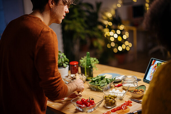 man kookt voor kerstdiner en kijkt een kookvideo