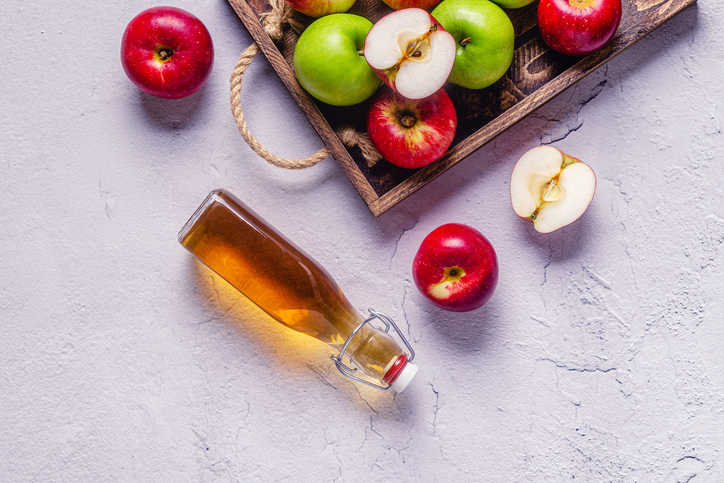 Houten dienblad met appels en liggend een flesje appelazijn